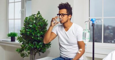 Man drinking a glass of water while receiving Ig therapy.