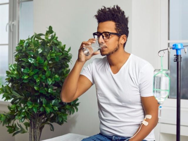 Man drinking a glass of water while receiving Ig therapy.
