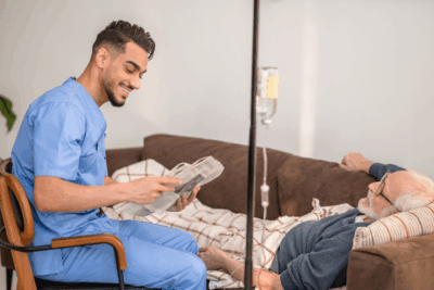 A male patient laying on the couch receiving Ig therapy with a nurse reading to him