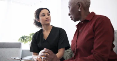 Nurse answering a patient's medical questions in a home setting.