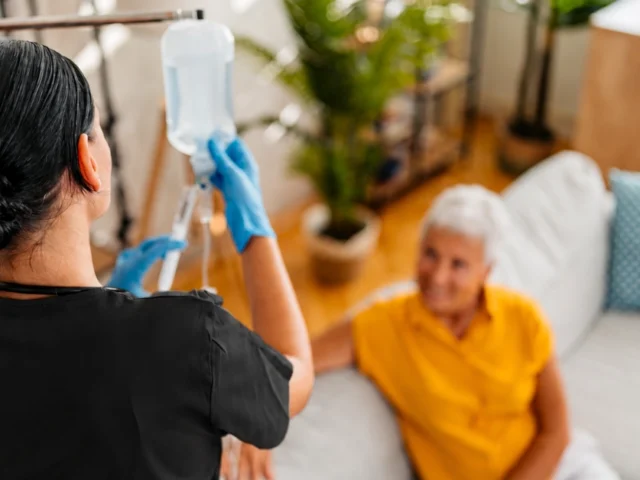 Nurse administering infusion therapy at home.